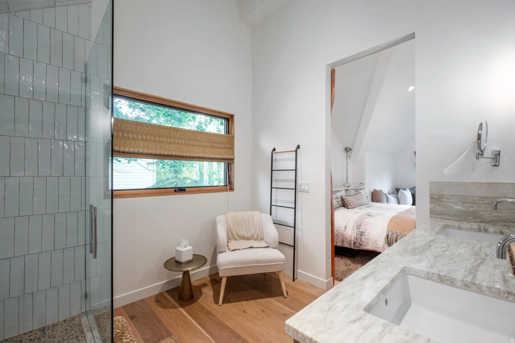 Bathroom featuring a glass-enclosed shower with vertical subway tile, a rectangular window with wood trim, wood-finish flooring, and a vanity with an integrated sink and stone countertop