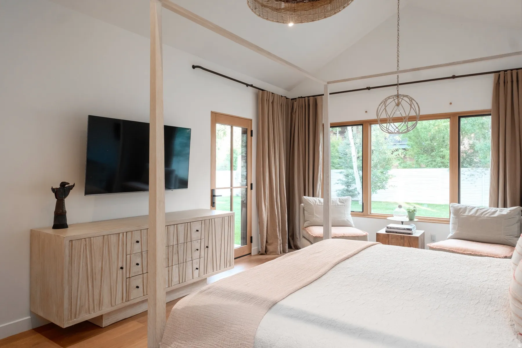 Vaulted ceilings define this space, featuring wide windows with wood-frame construction and a glass-paneled door