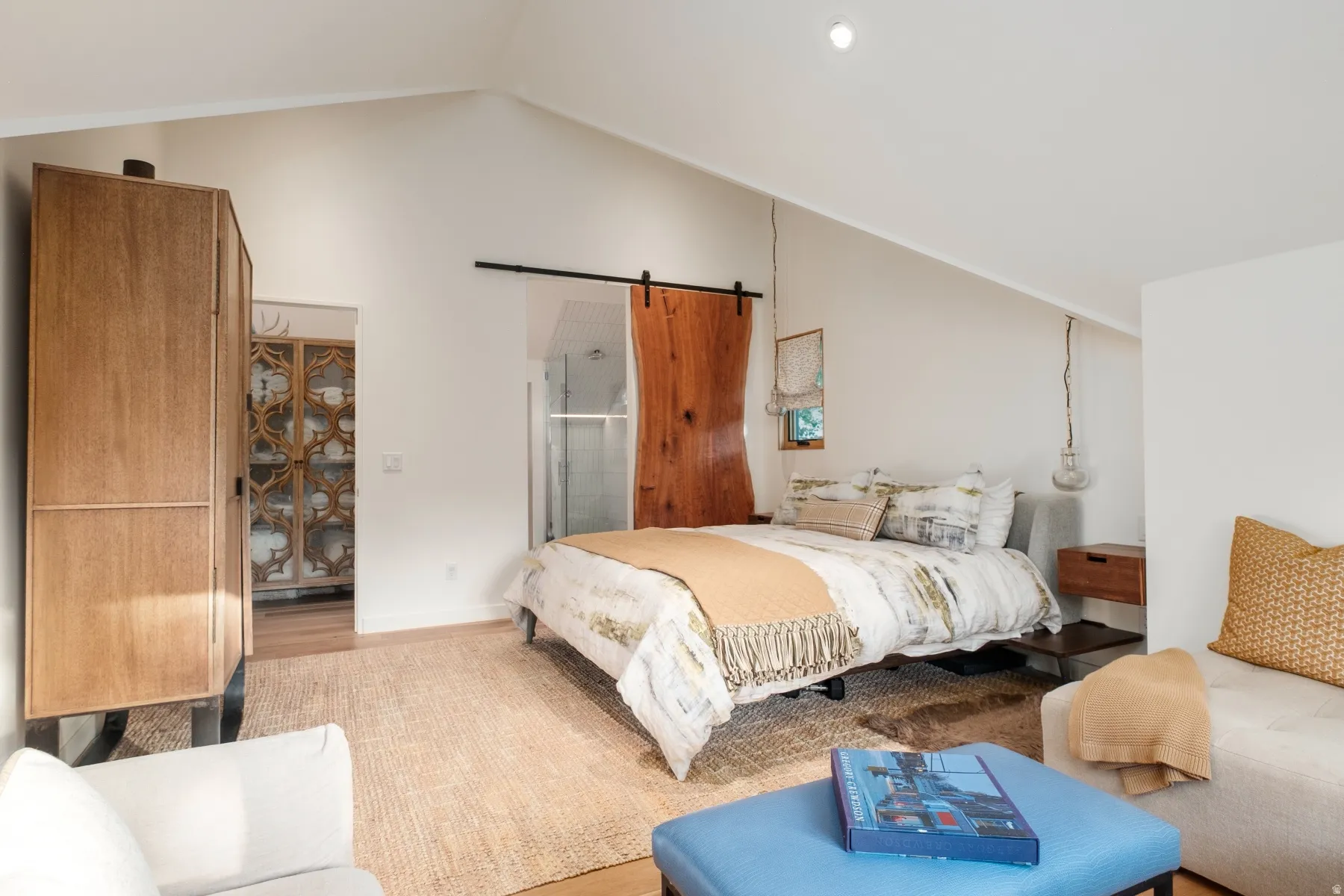 Vaulted ceiling bedroom featuring a live-edge barn door, recessed lighting, and wood-finish flooring
