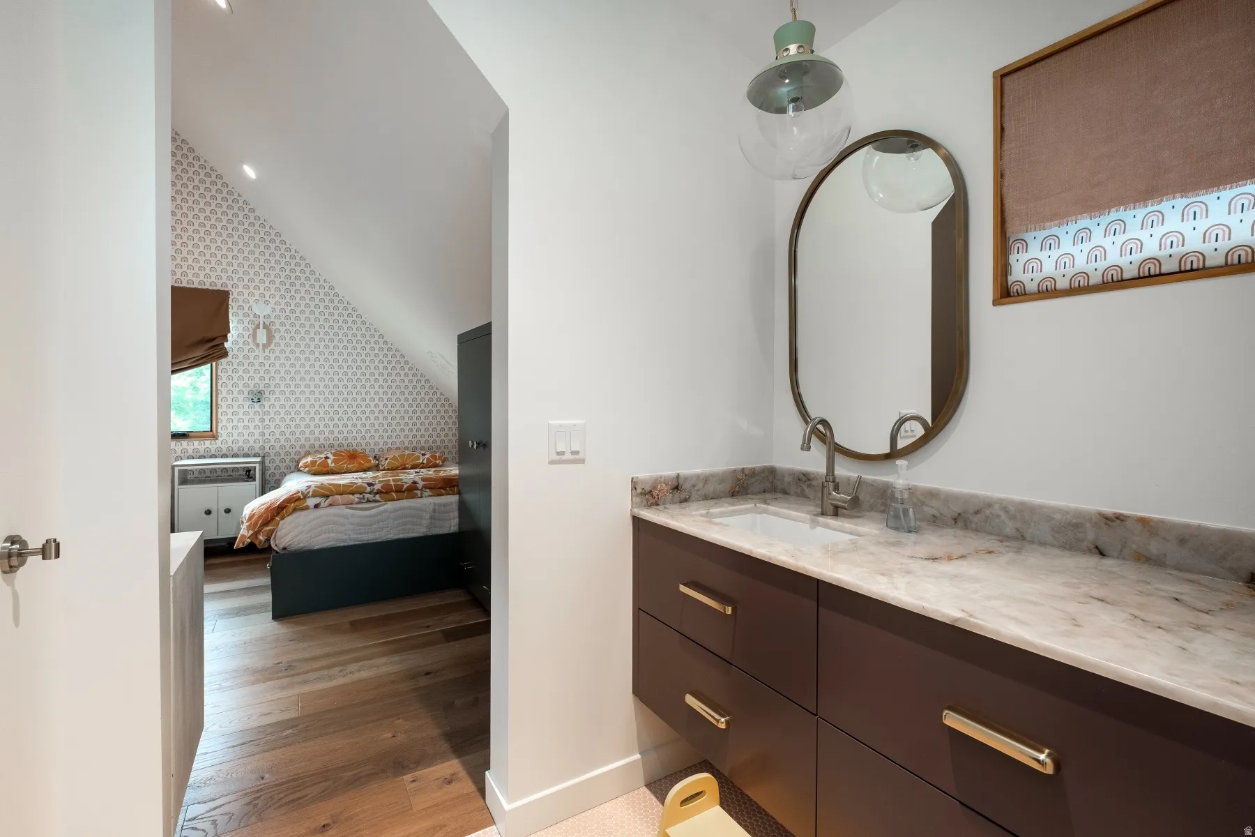 Floating vanity with stone countertop and integrated sink, complemented by a contemporary oval mirror