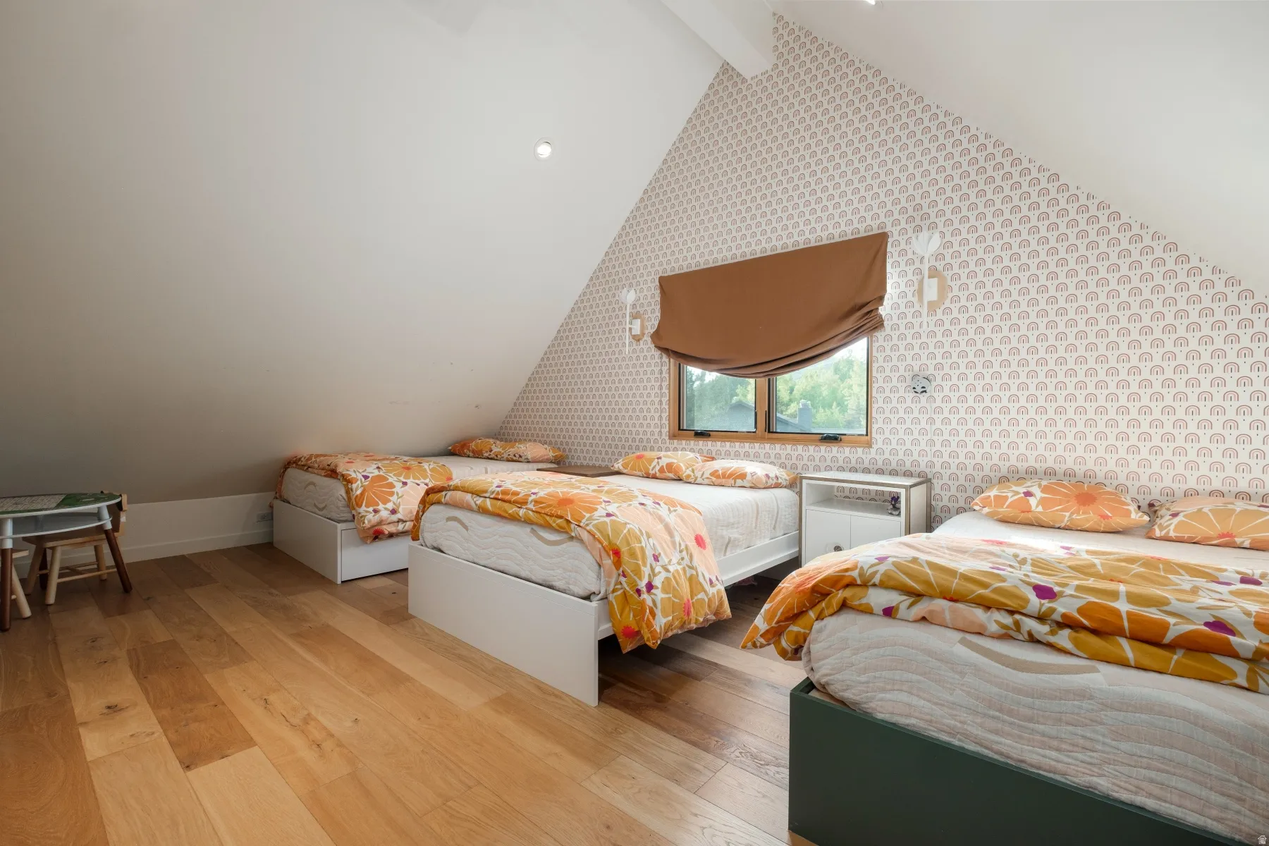 Attic space featuring wood-finish flooring, an angled ceiling, and a patterned accent wall