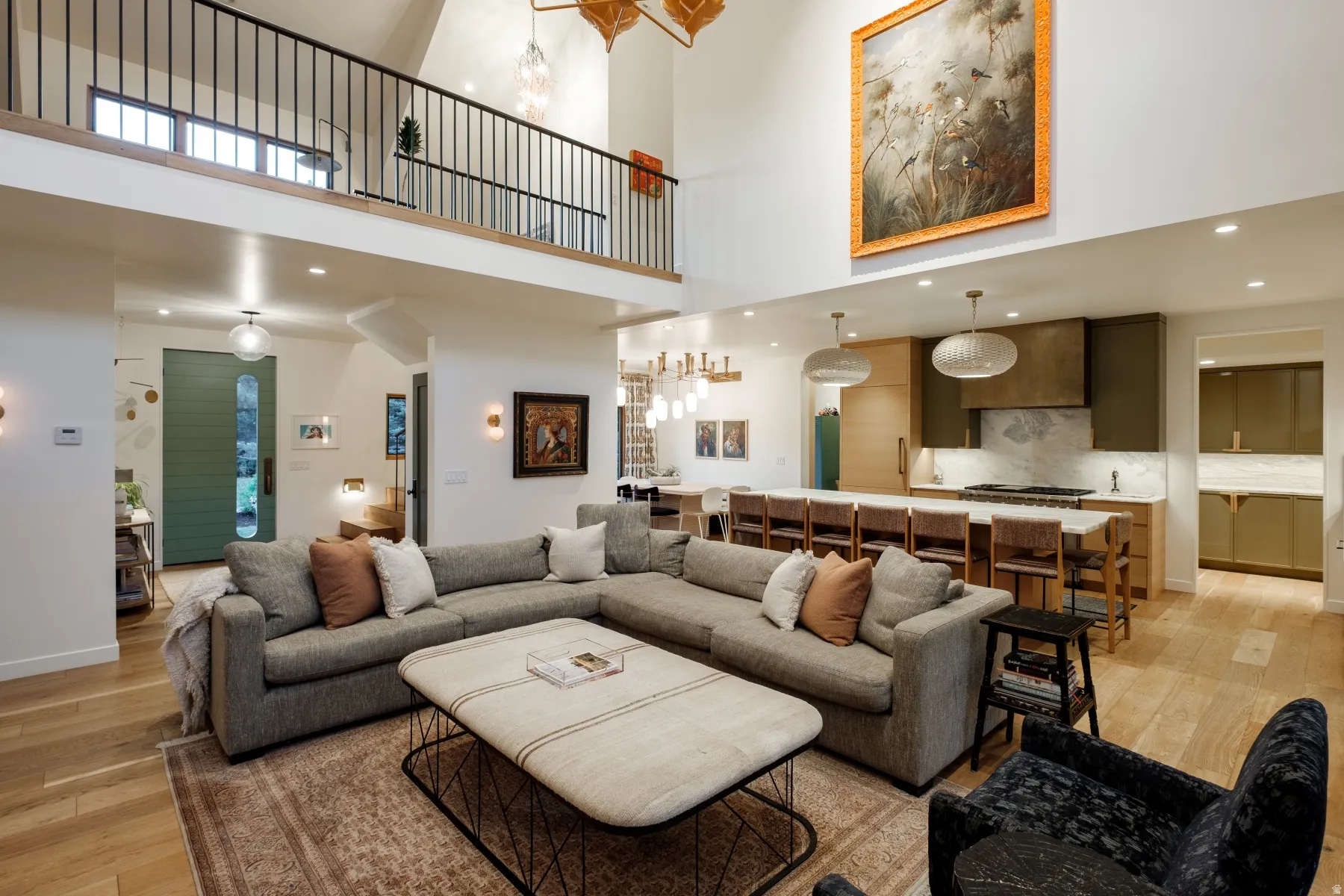 Spacious open-concept living area featuring high ceilings, wood-finish flooring, and a second-story balcony with iron railing