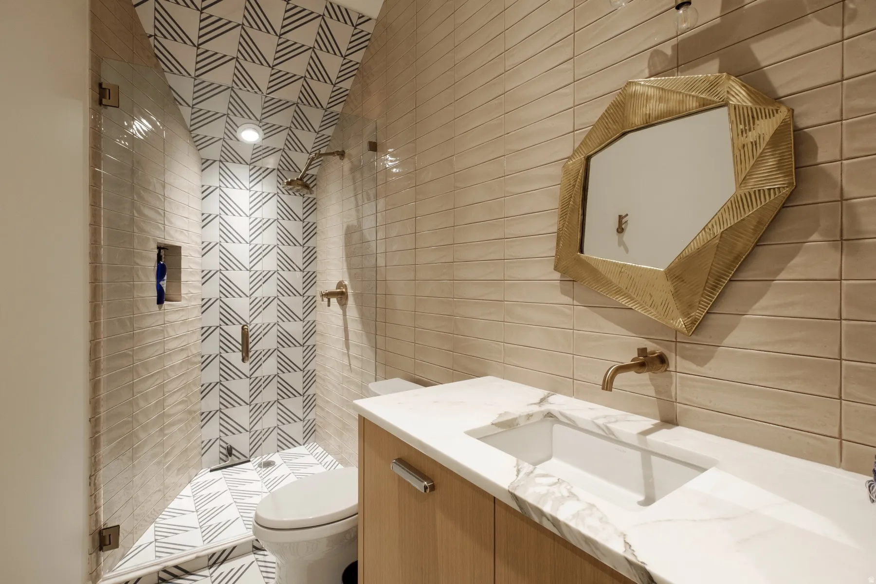Full bathroom featuring a walk-in shower with patterned tile, a wall-mounted brass shower head, and a built-in shower niche