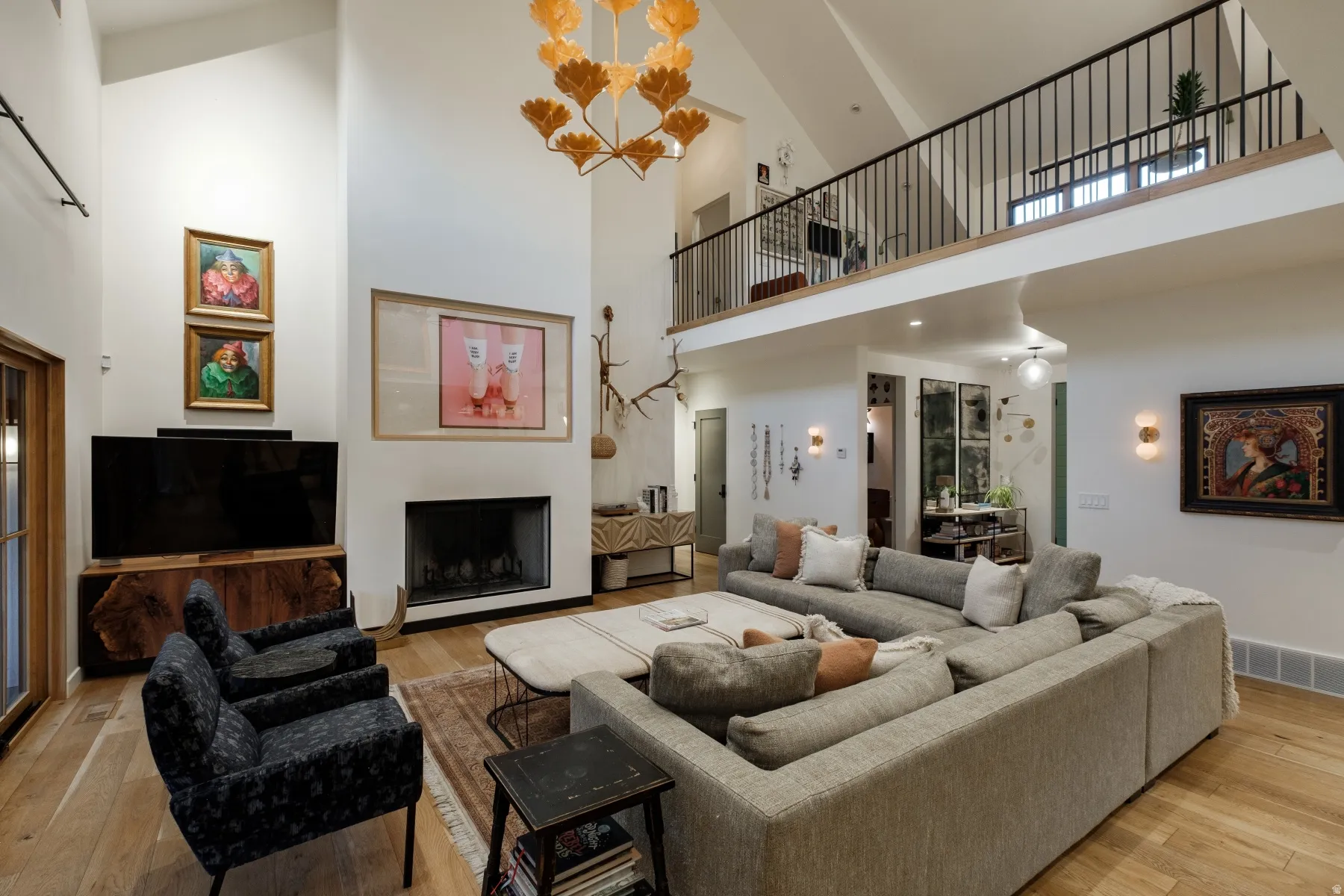 Spacious living area featuring high vaulted ceilings, light wood-finish flooring, and a contemporary fireplace