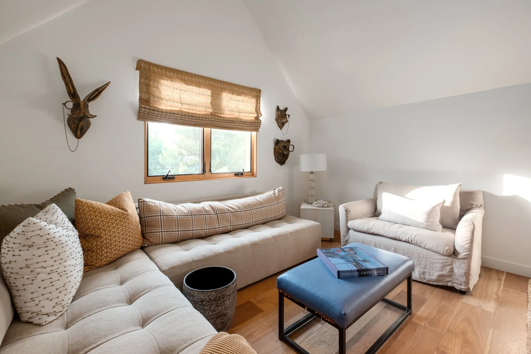 Attic lounge featuring a window with wood trim, sloped ceilings, and wood-finish flooring
