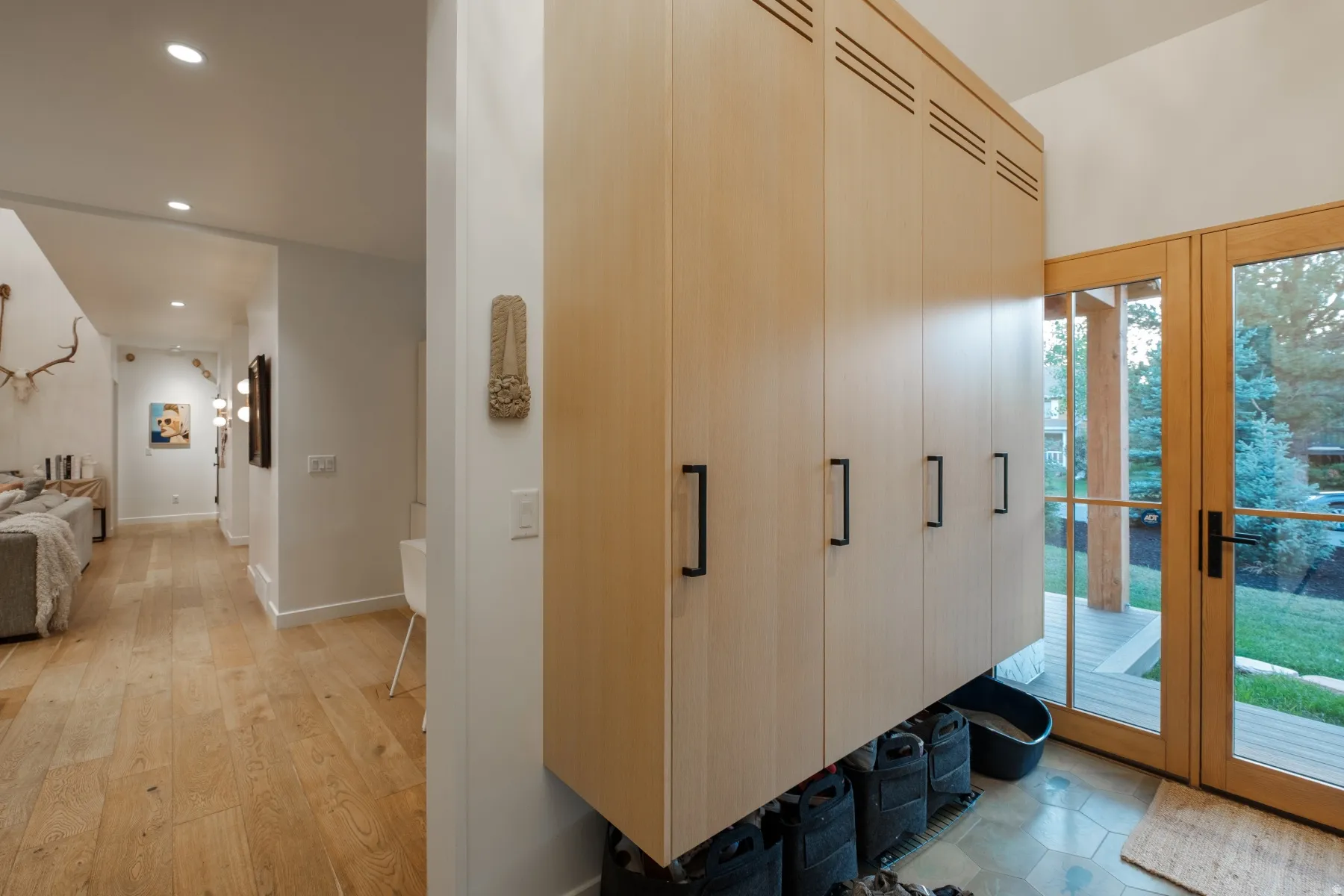 Entryway featuring light wood-finish cabinetry with black hardware, hexagonal floor tiling, and a double glass-paned door