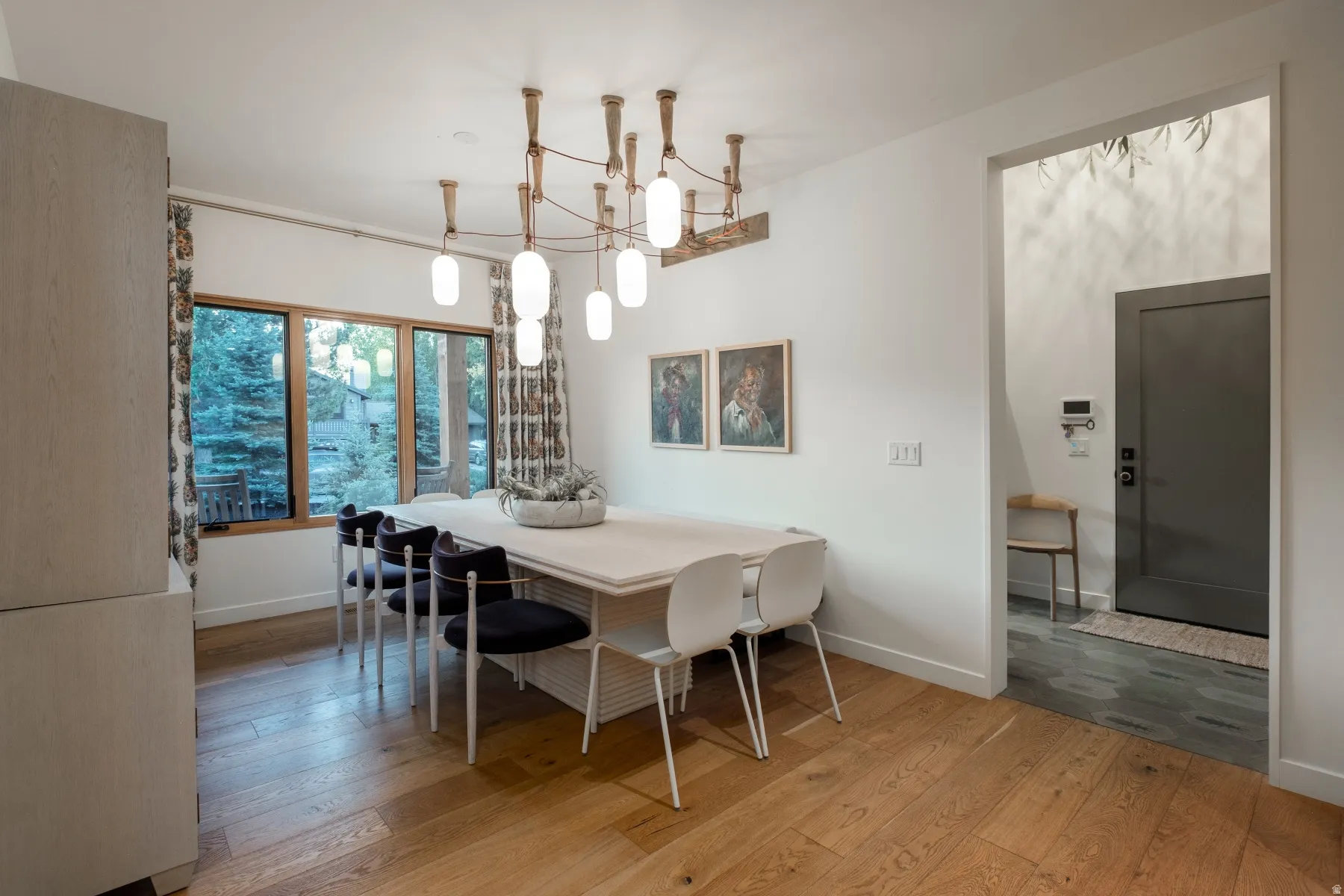 Dining area featuring wood-finish flooring, a contemporary chandelier, and large windows with wood trim