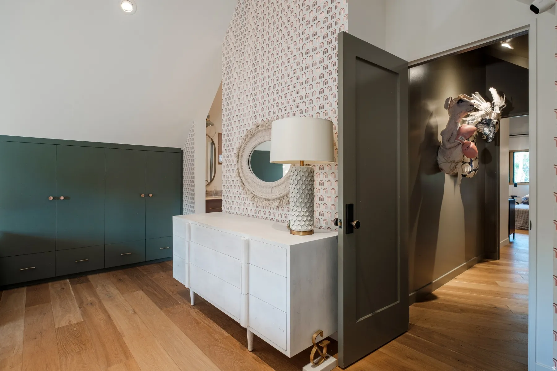 Hardwood flooring extends through this space featuring built-in green cabinetry with wood knobs