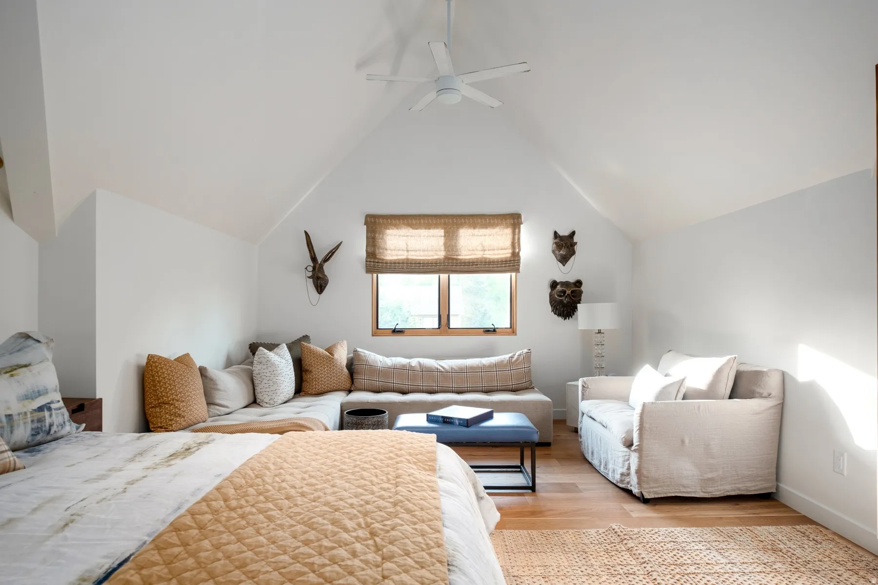 Spacious room featuring vaulted ceilings, wood-finish flooring, a built-in window bench, and a modern ceiling fan