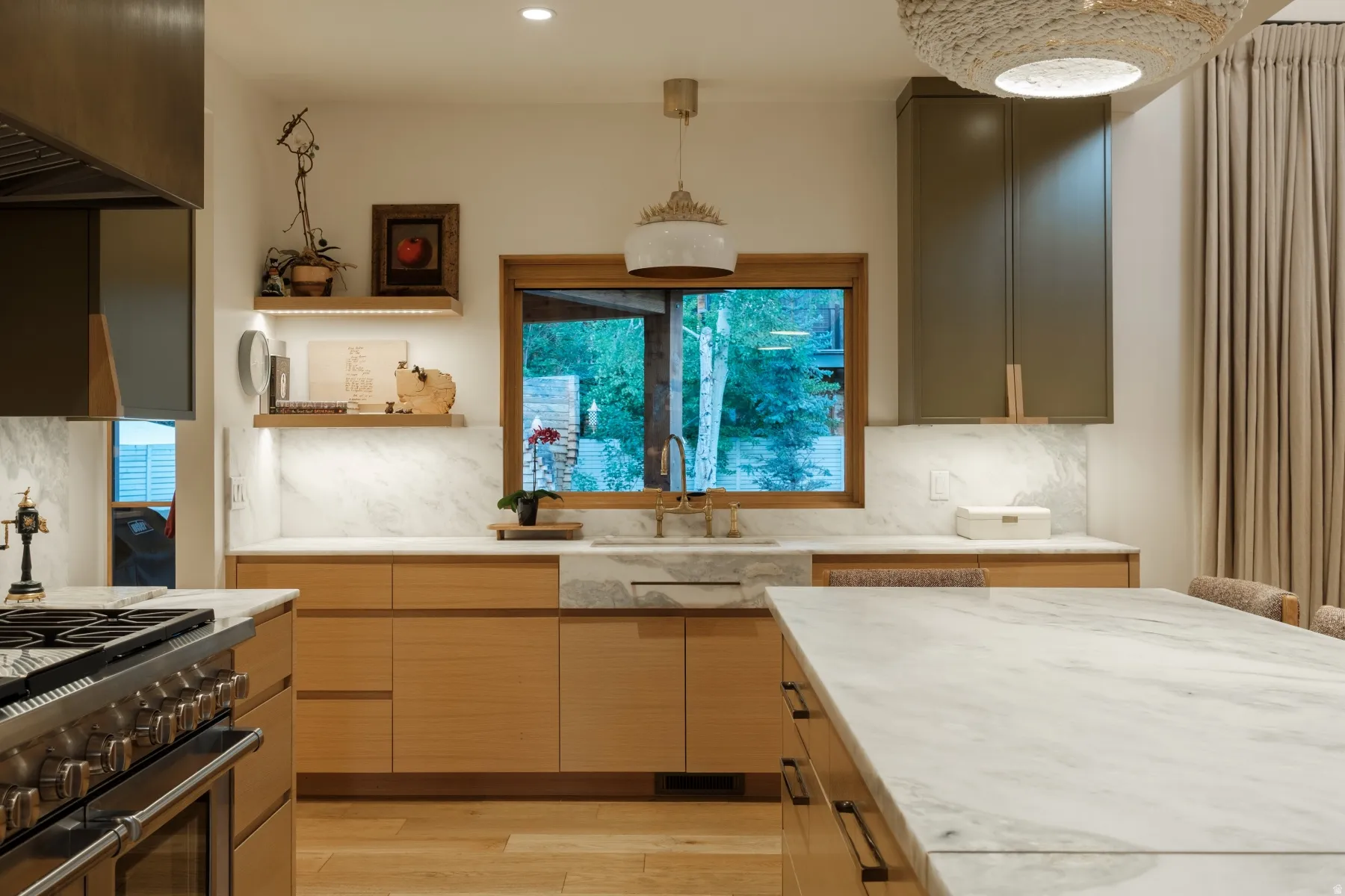 Modern kitchen with light wood-finish cabinetry, a large window over the sink, and a substantial island