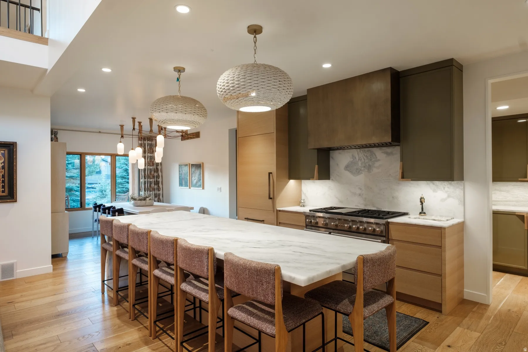 Extended kitchen island with stone countertop, accompanied by light wood-finish flooring