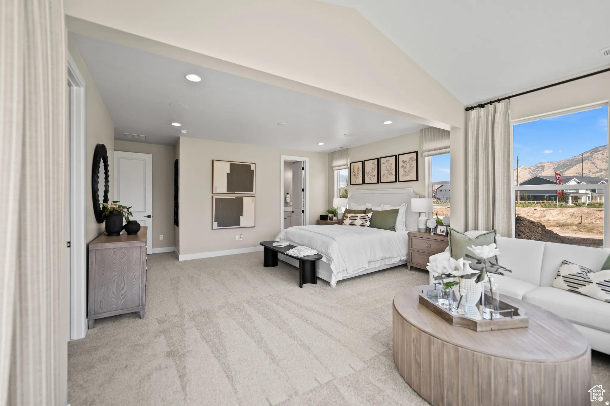 Spacious room featuring neutral carpeting, recessed lighting, expansive windows, a mountain backdrop, and light-toned walls