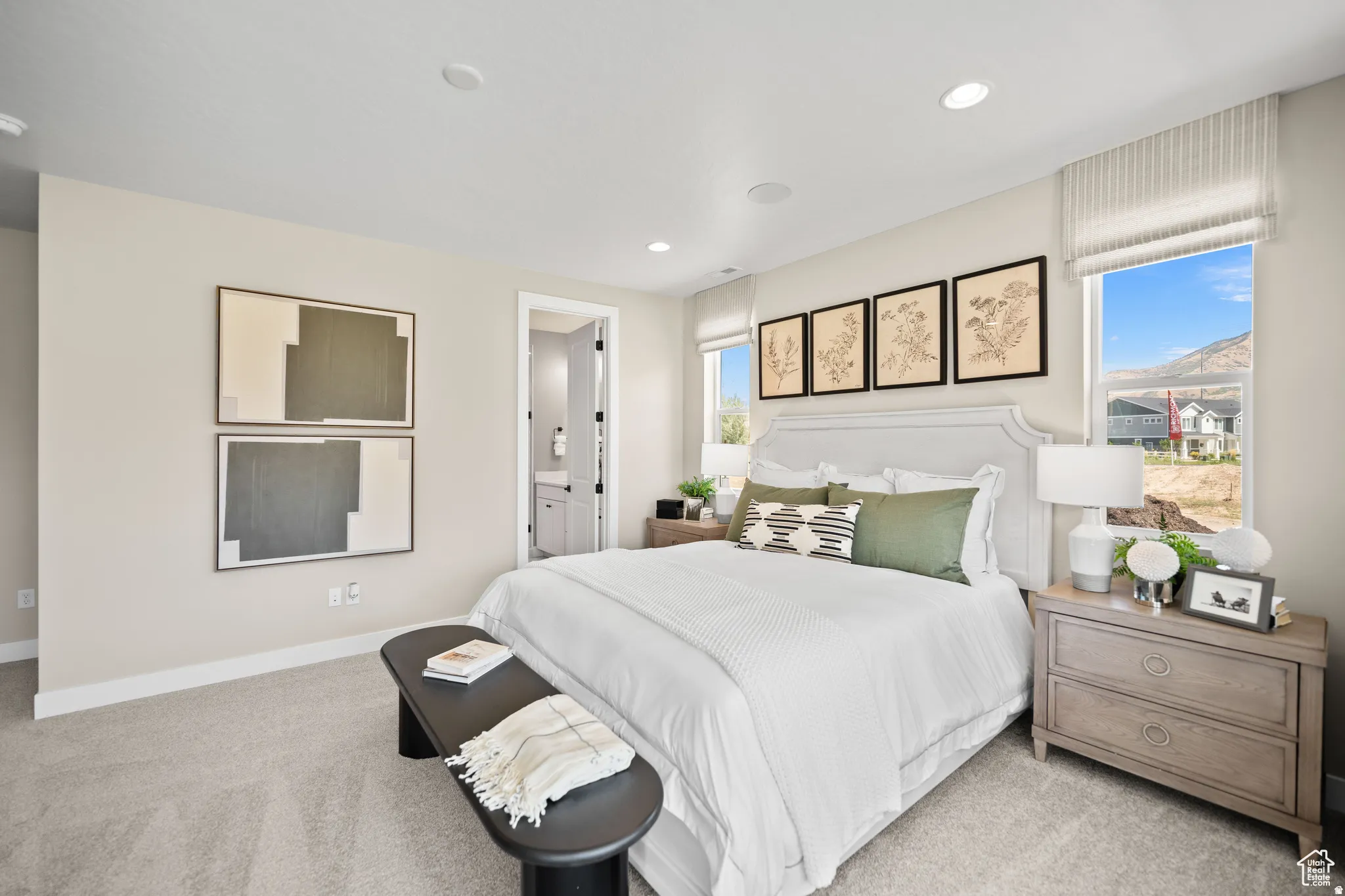 Carpeted bedroom featuring recessed lighting, multiple windows, and a doorway opening to a bathroom with a vanity