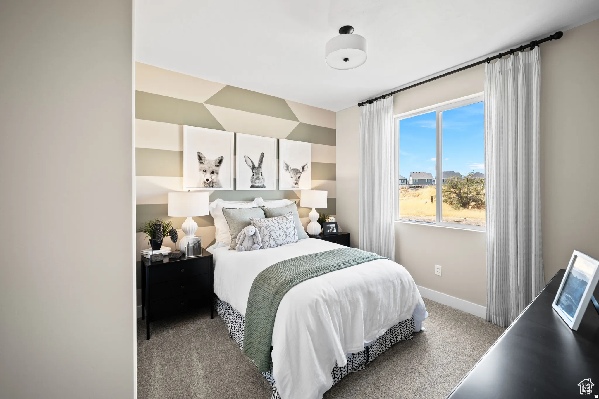Bedroom featuring neutral-toned walls, geometric accent wall, a window with natural light, a ceiling-mounted light fixture, and carpeted flooring