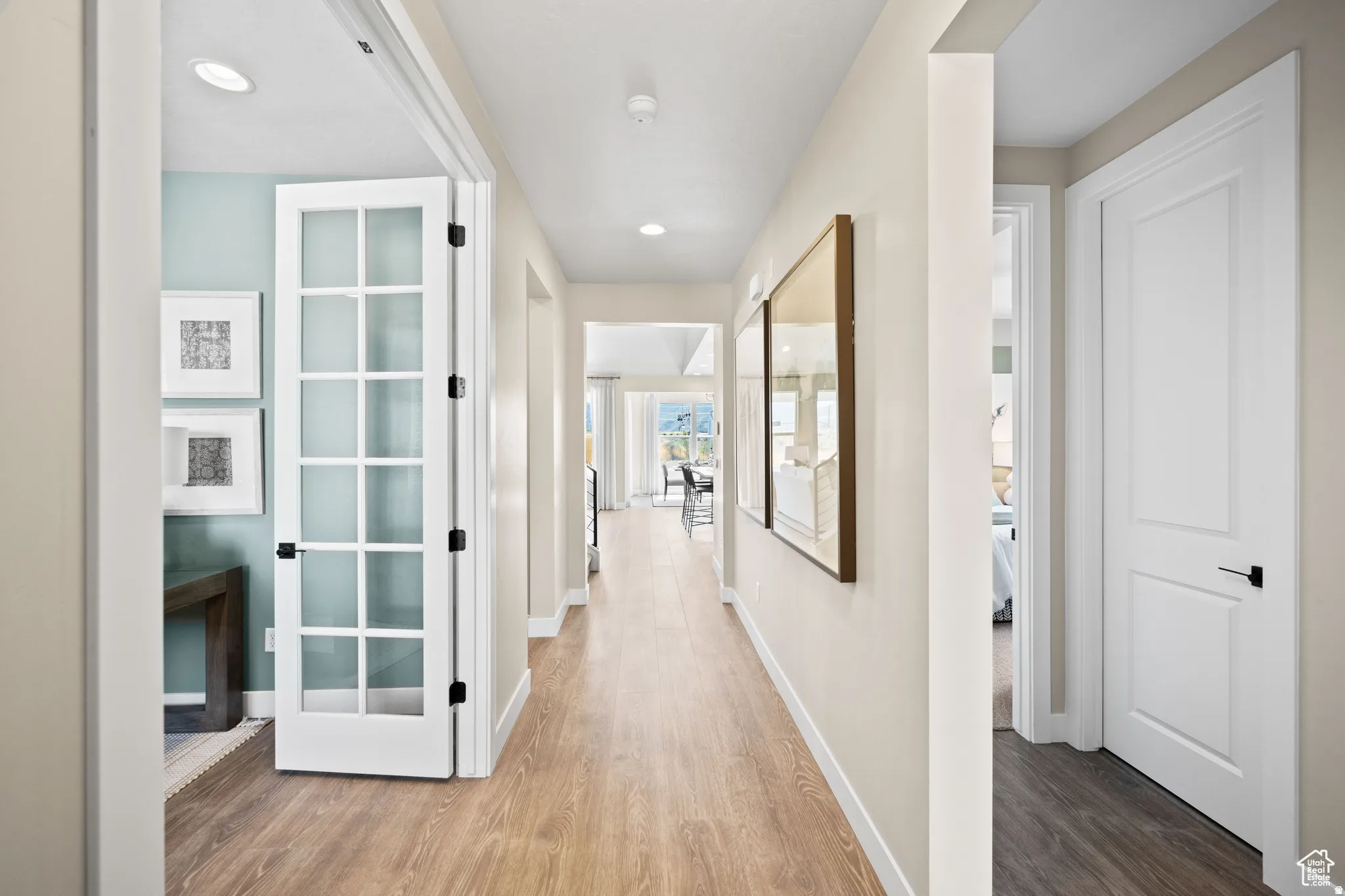 Spacious hallway featuring wood-finish flooring, recessed lighting, and a frosted French door