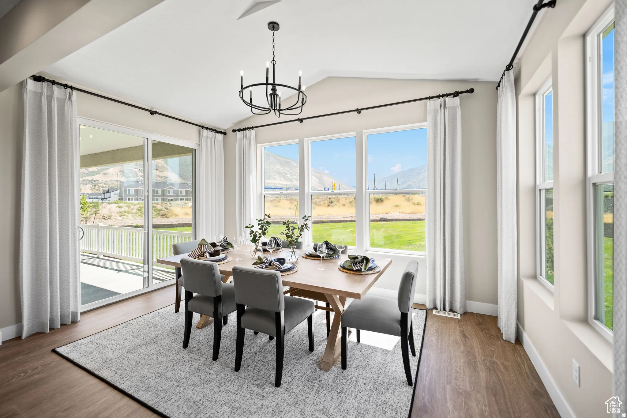 Bright dining space featuring a vaulted ceiling and a contemporary chandelier