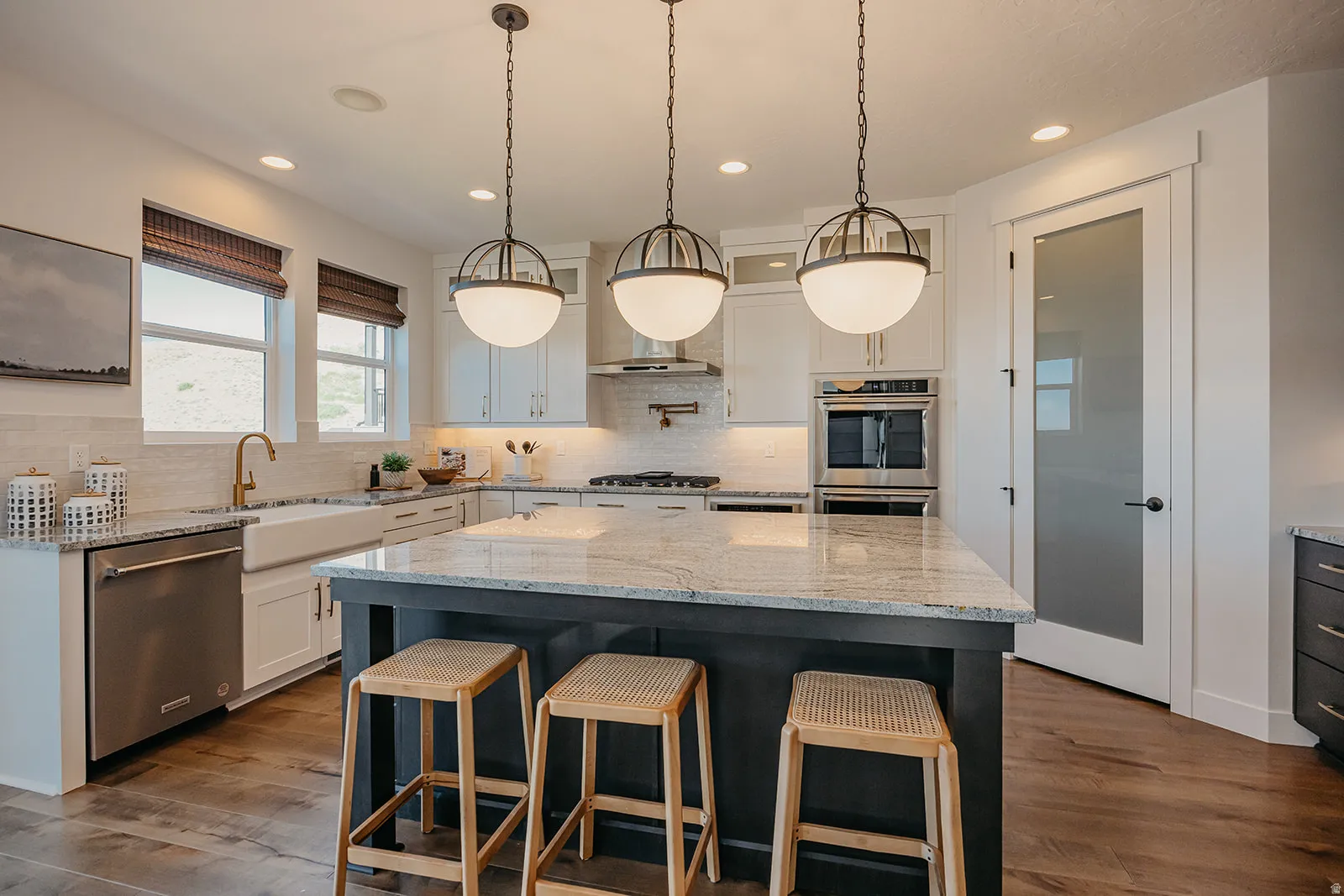 Kitchen featuring a central island with granite countertop, perimeter cabinetry, stainless steel appliances, and wood-finish flooring