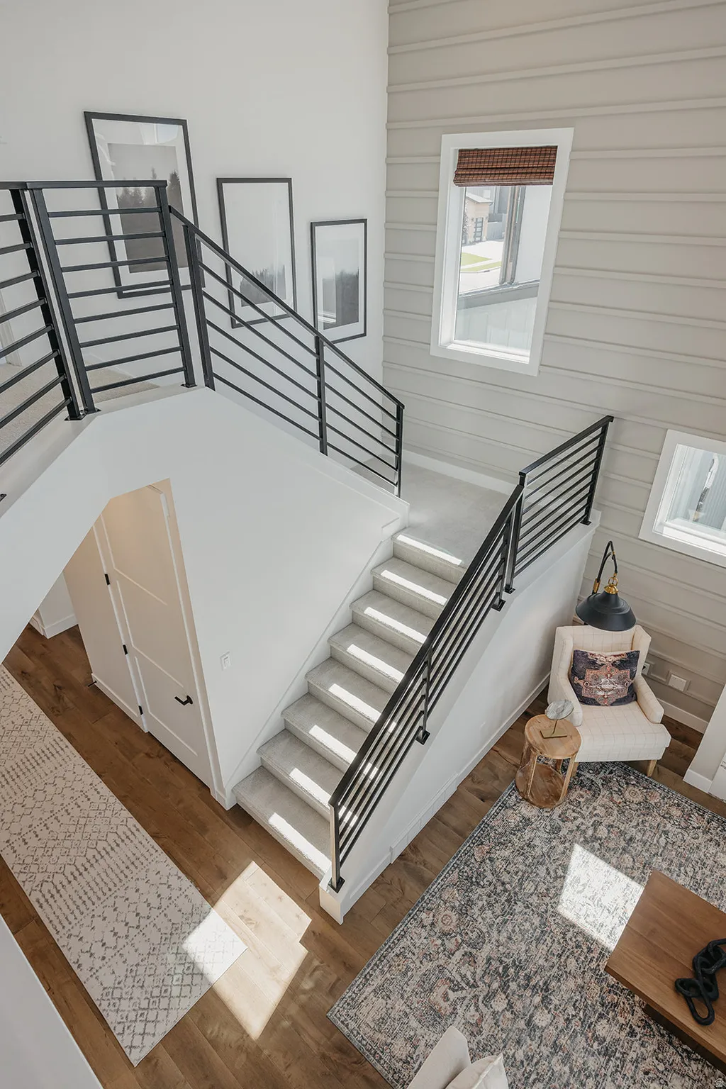 Modern staircase with black metal railings and light gray carpeted steps