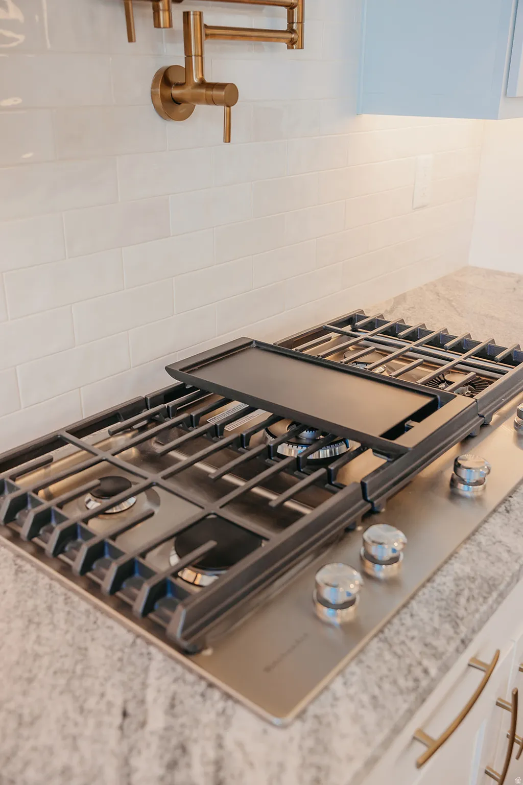 Built-in gas cooktop with a griddle feature, set into a speckled countertop
