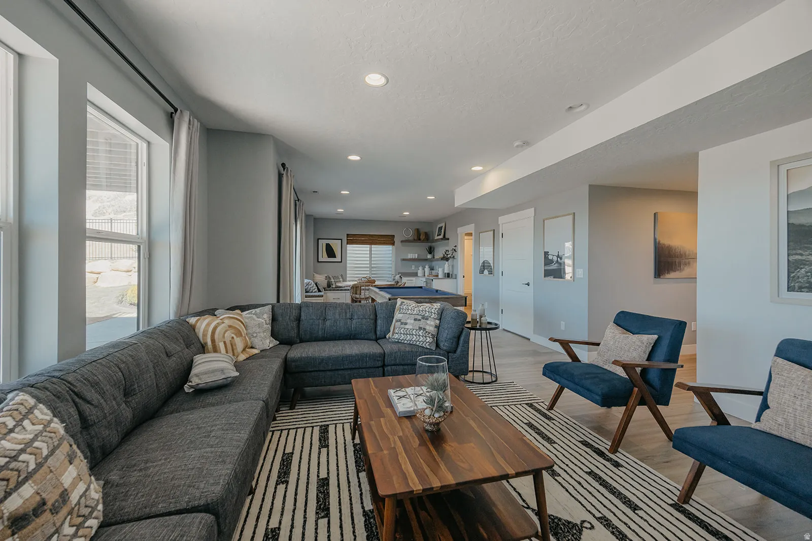 Spacious living area featuring large windows, recessed lighting, light wood-finish flooring, and a neutral color palette