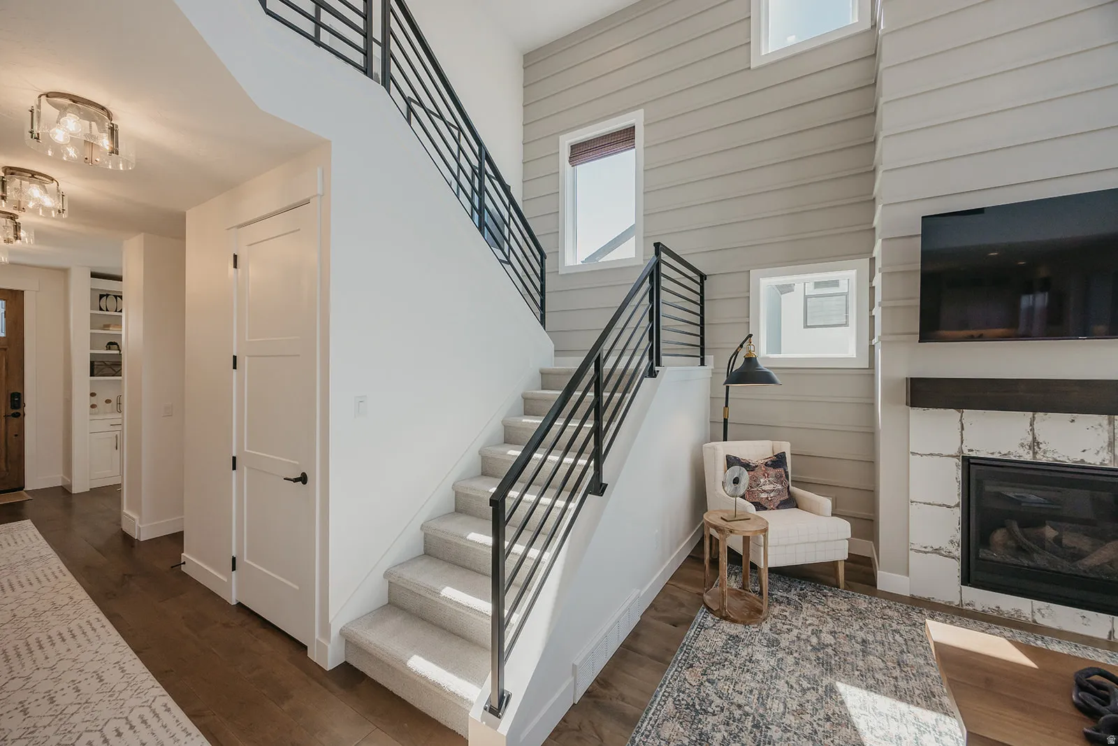 Two-story entry featuring wood-finish flooring, a carpeted staircase with contemporary metal railings, and a shiplap accent wall