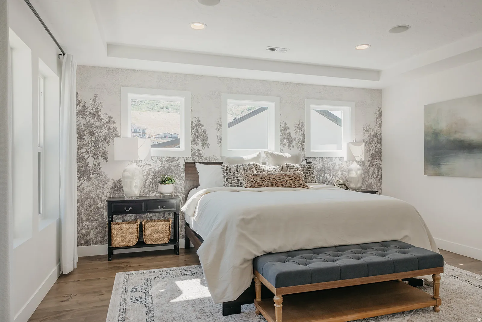 Spacious bedroom featuring recessed lighting, tray ceiling details, wood-finish flooring, and multiple windows