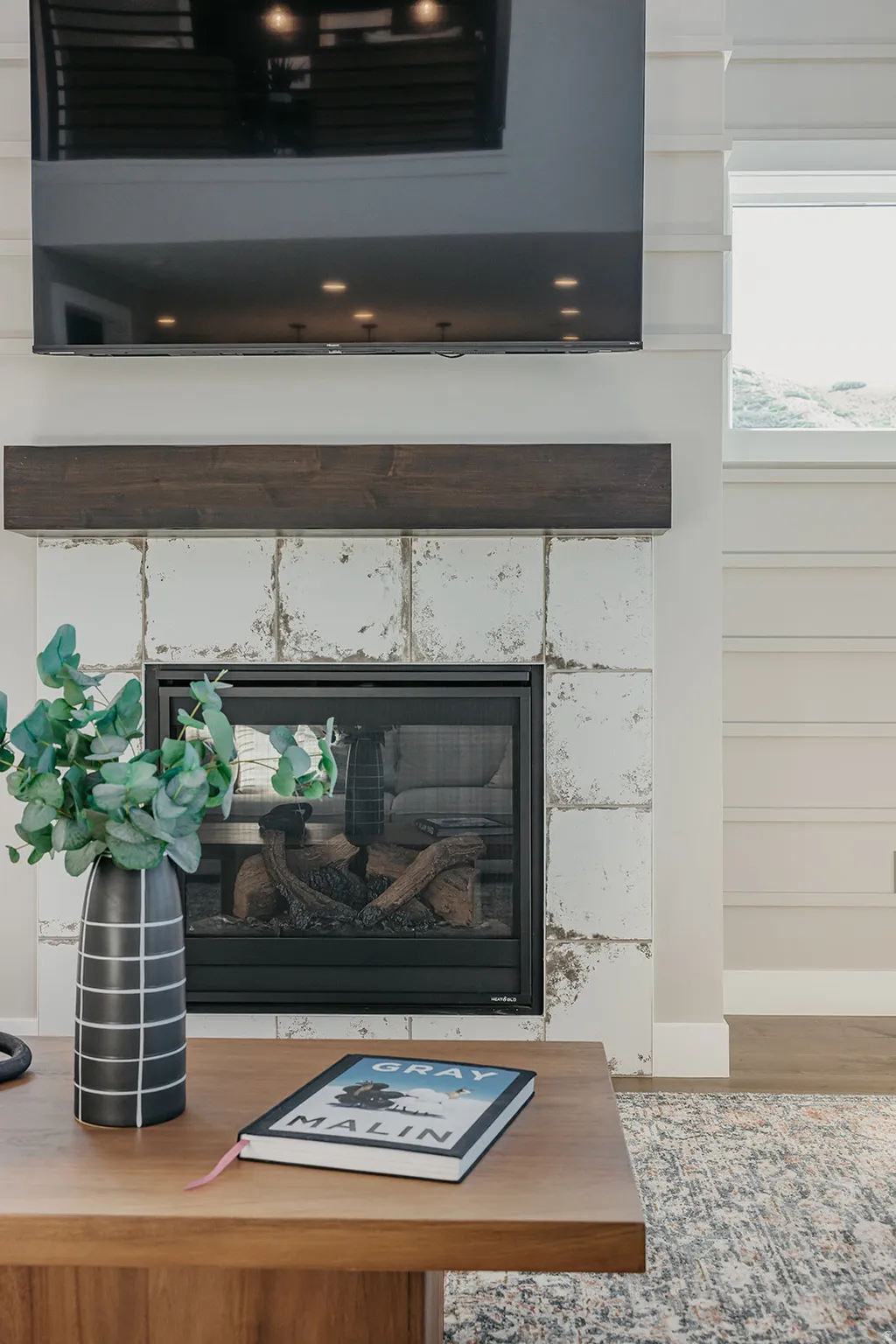 Built-in fireplace featuring a white distressed tile surround and a dark wood mantel