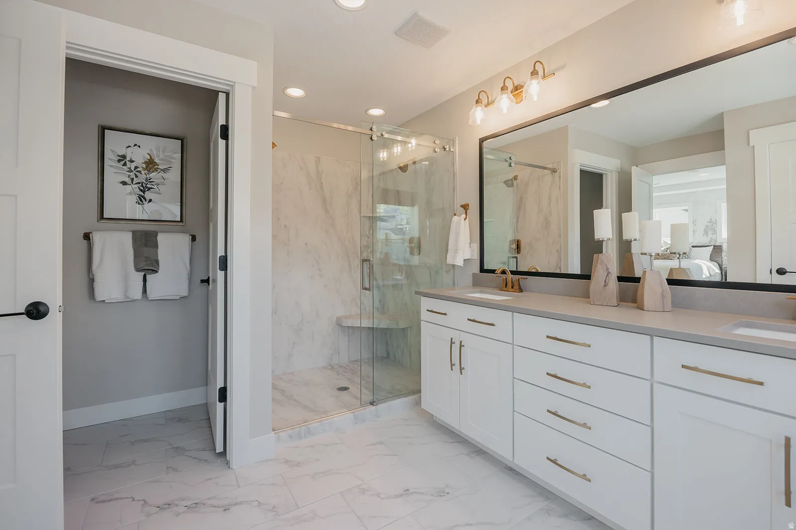 Spacious bathroom featuring a dual vanity with white cabinetry and gold-finish hardware