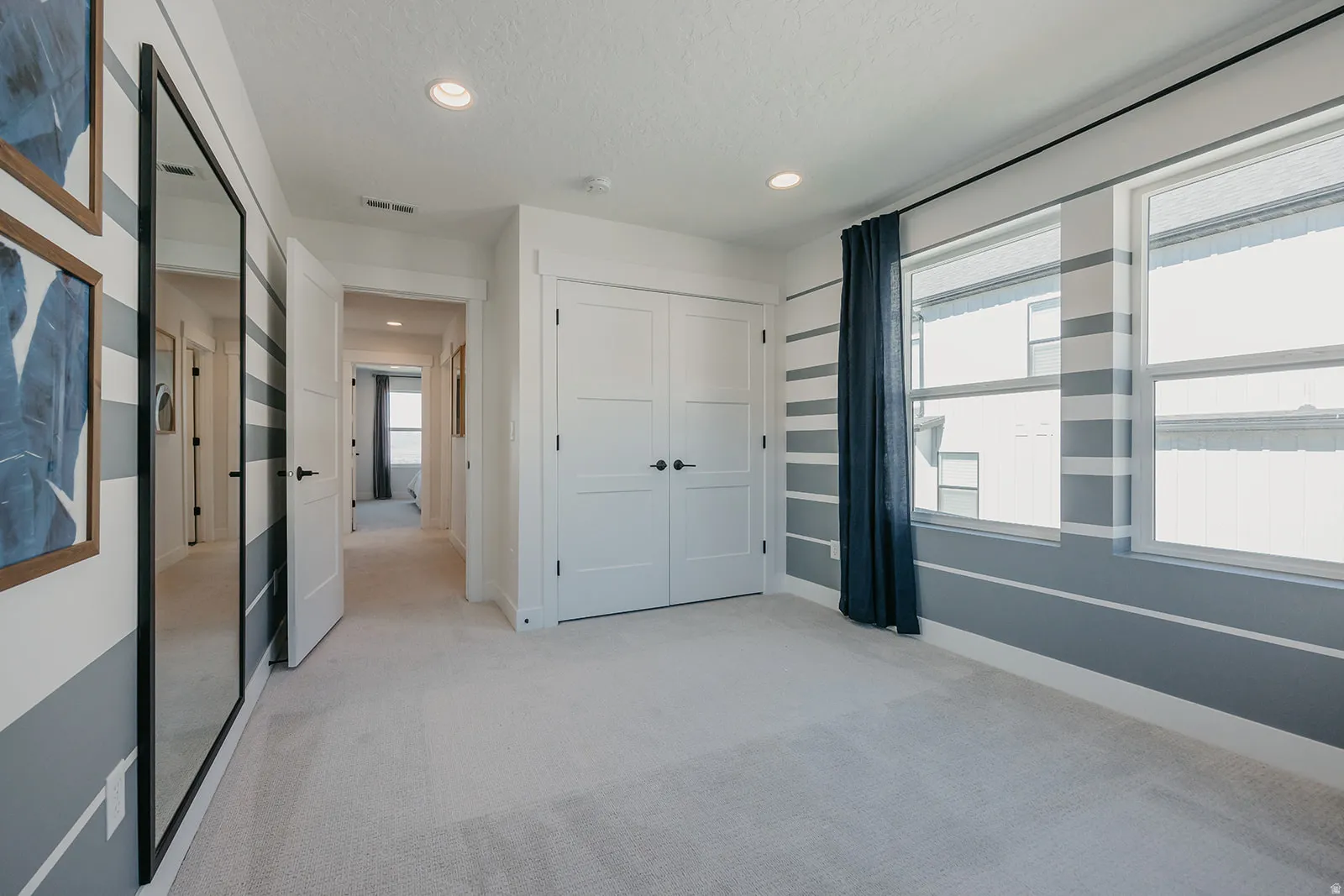 Carpeted room featuring dual windows with dark drapery, a three-panel closet door, and recessed lighting