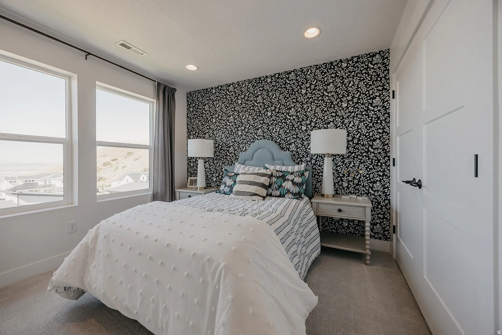 Bedroom featuring two large windows with white trim, patterned accent wall, recessed lighting, and light gray carpet