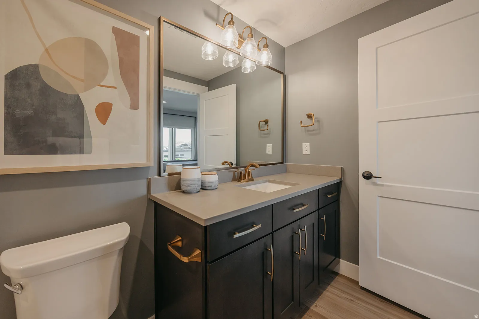 Vanity area featuring a grey countertop, undermount sink, and dark wood-finish cabinetry with gold-tone hardware