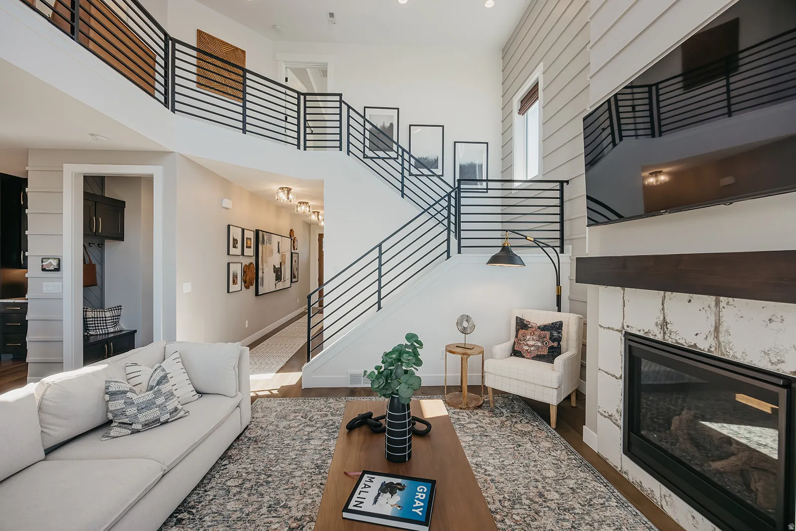 Two-story living area featuring a prominent staircase with black horizontal bar railings