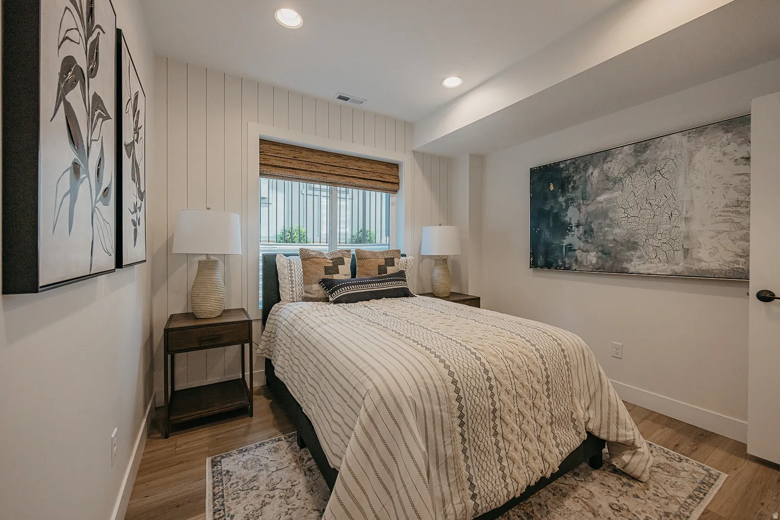 Wood-finish flooring with white baseboards, recessed lighting, and a window with a woven shade