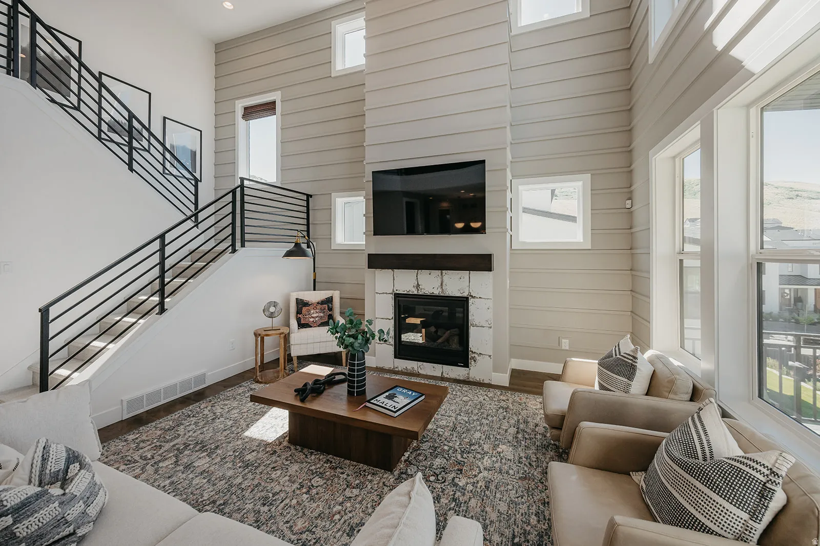 Two-story living area featuring a prominent fireplace with a stone surround and wood mantel