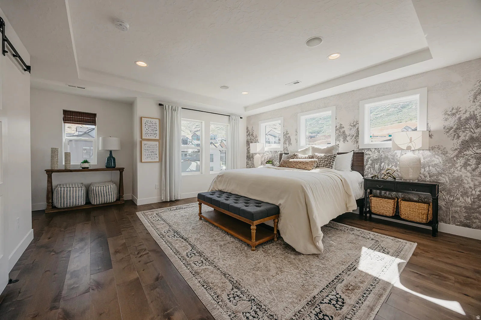 Spacious room featuring wood-finish flooring, a tray ceiling with recessed lighting, and multiple windows