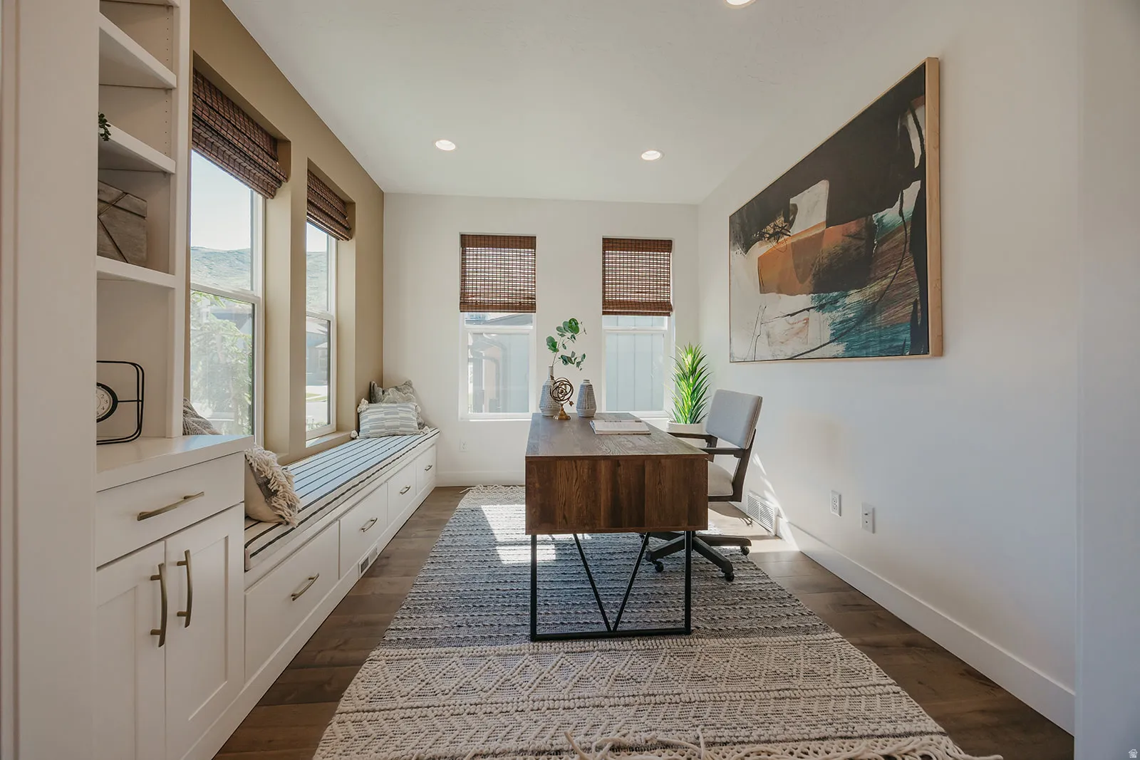Dedicated office space featuring expansive built-in window seating with integrated storage drawers