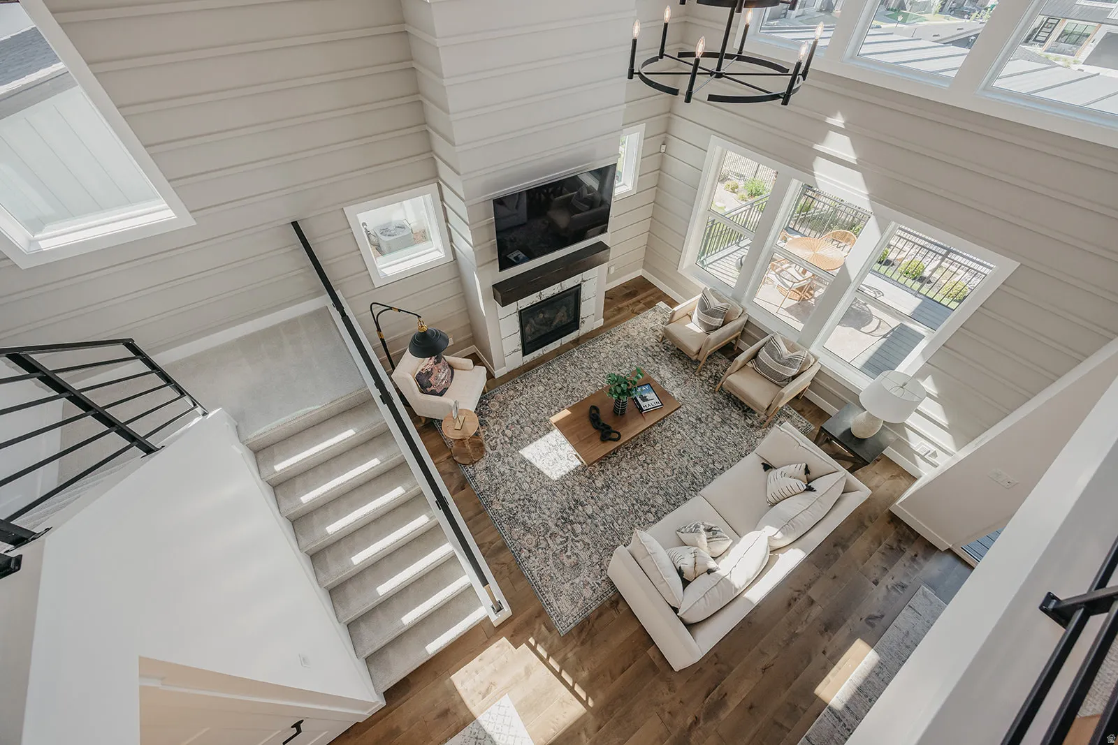 Two-story living area with high ceilings, horizontal plank walls, and wood-finish flooring