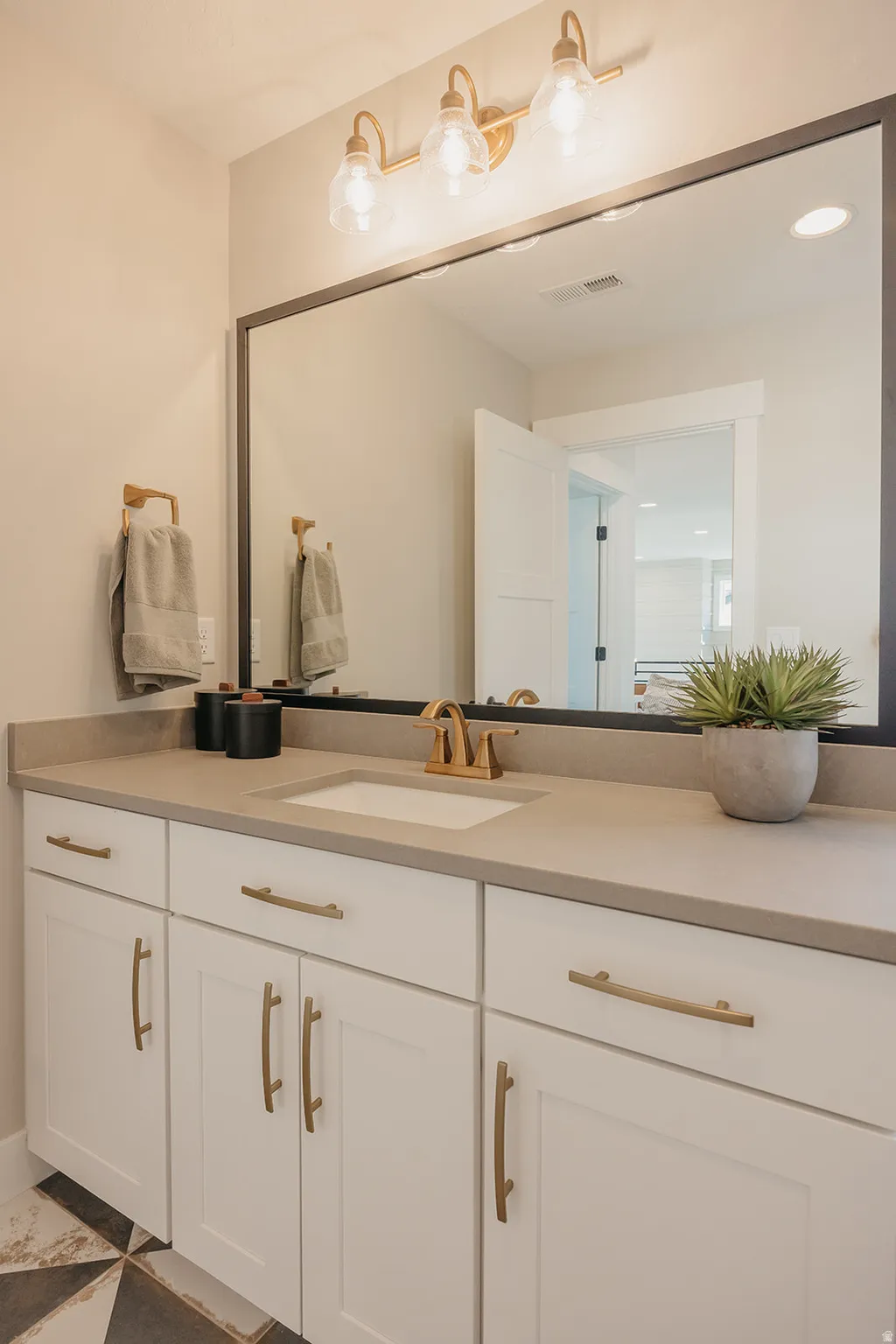 Bathroom vanity featuring a single undermount sink, brass-finish faucet, and substantial countertop space