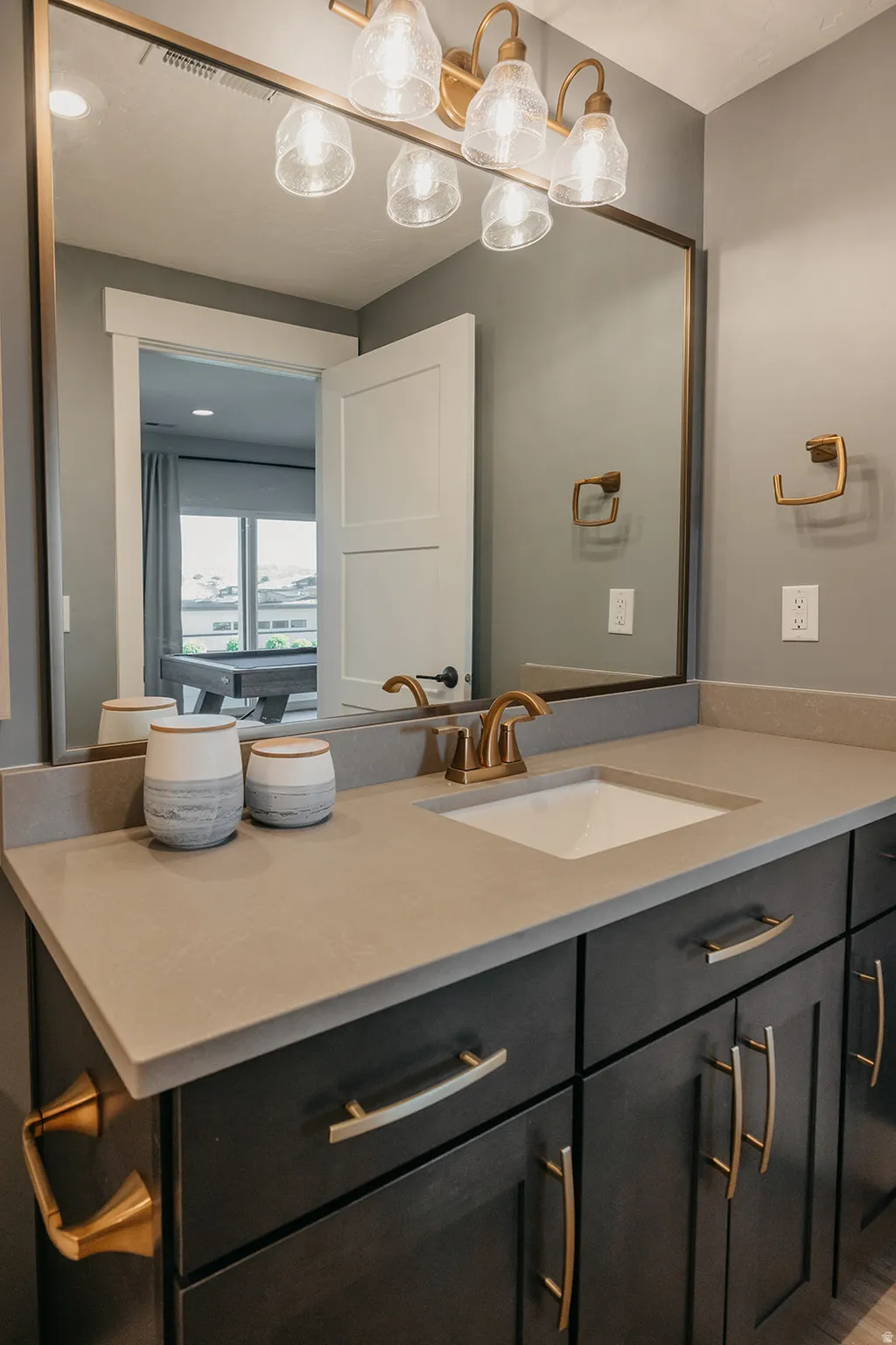 Bathroom vanity featuring dark wood cabinetry, a light-toned countertop with an integrated sink, and a gold-finish faucet