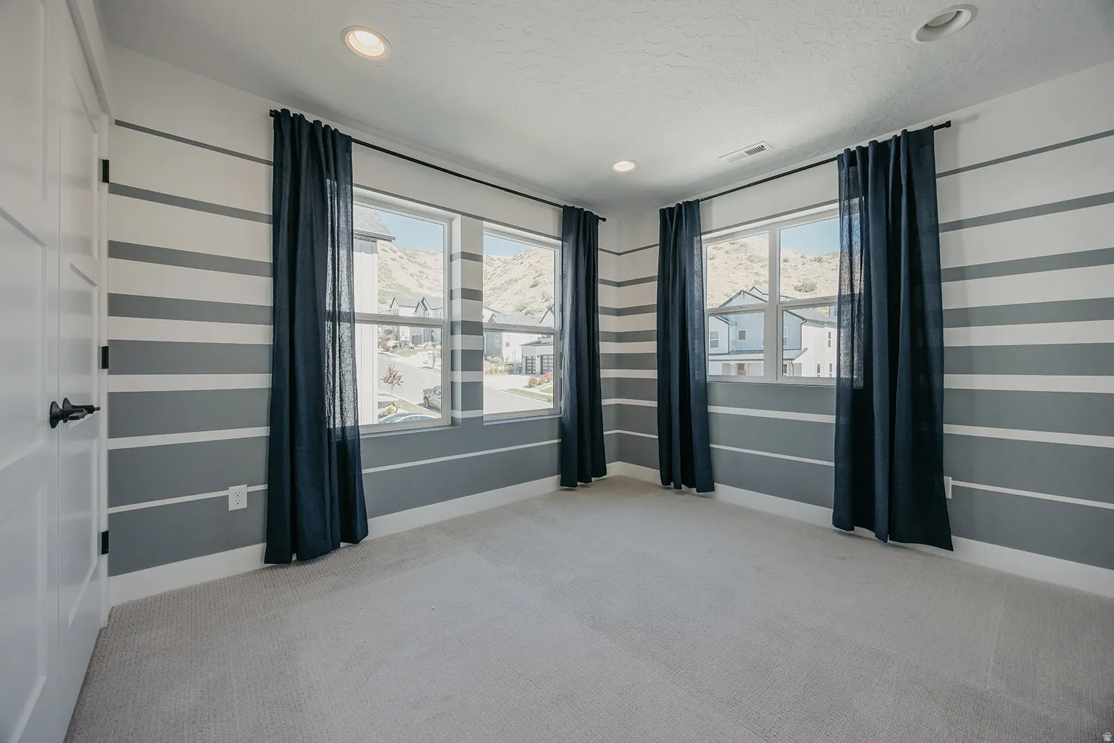 Room featuring horizontal striped accent walls, recessed lighting, and light-toned carpeting