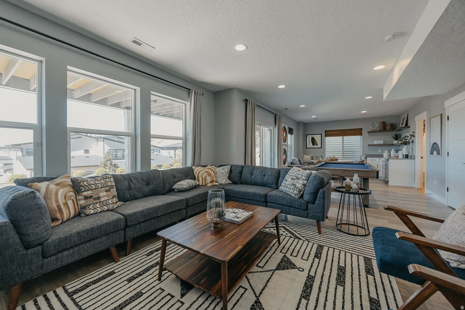 Spacious open-concept room featuring multiple large windows, recessed lighting, and wood-finish flooring
