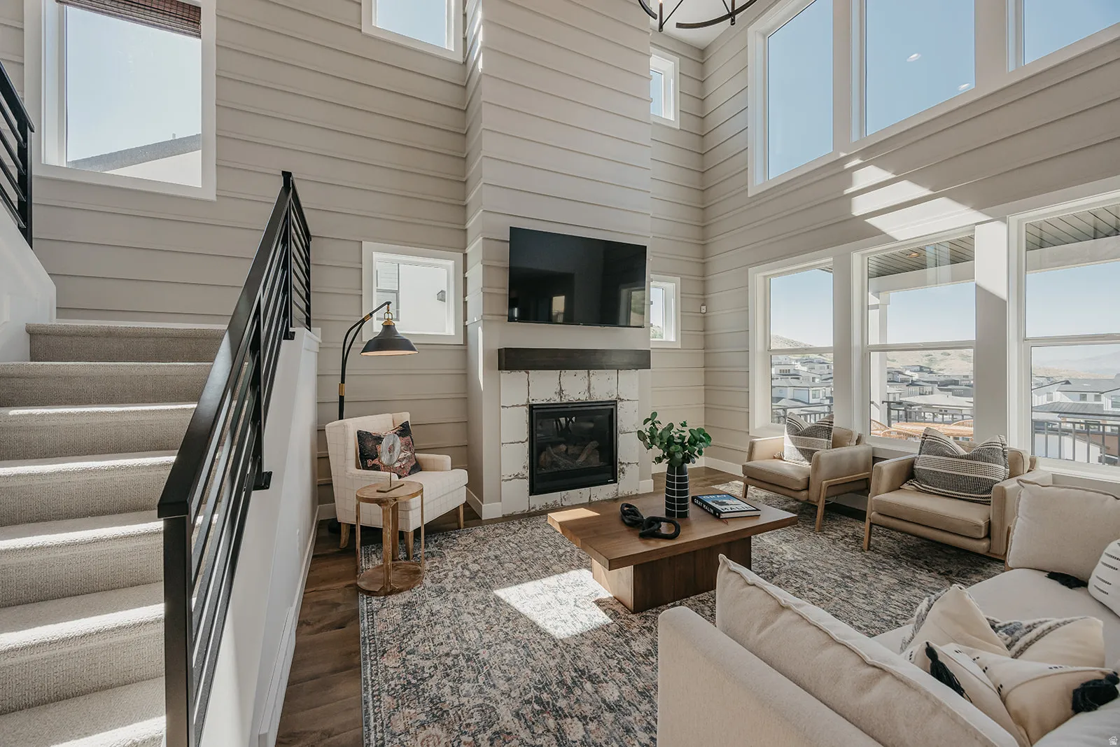 Two-story living area with high ceilings, horizontal plank wall finishes, and a stone-clad fireplace featuring a dark wood mantel