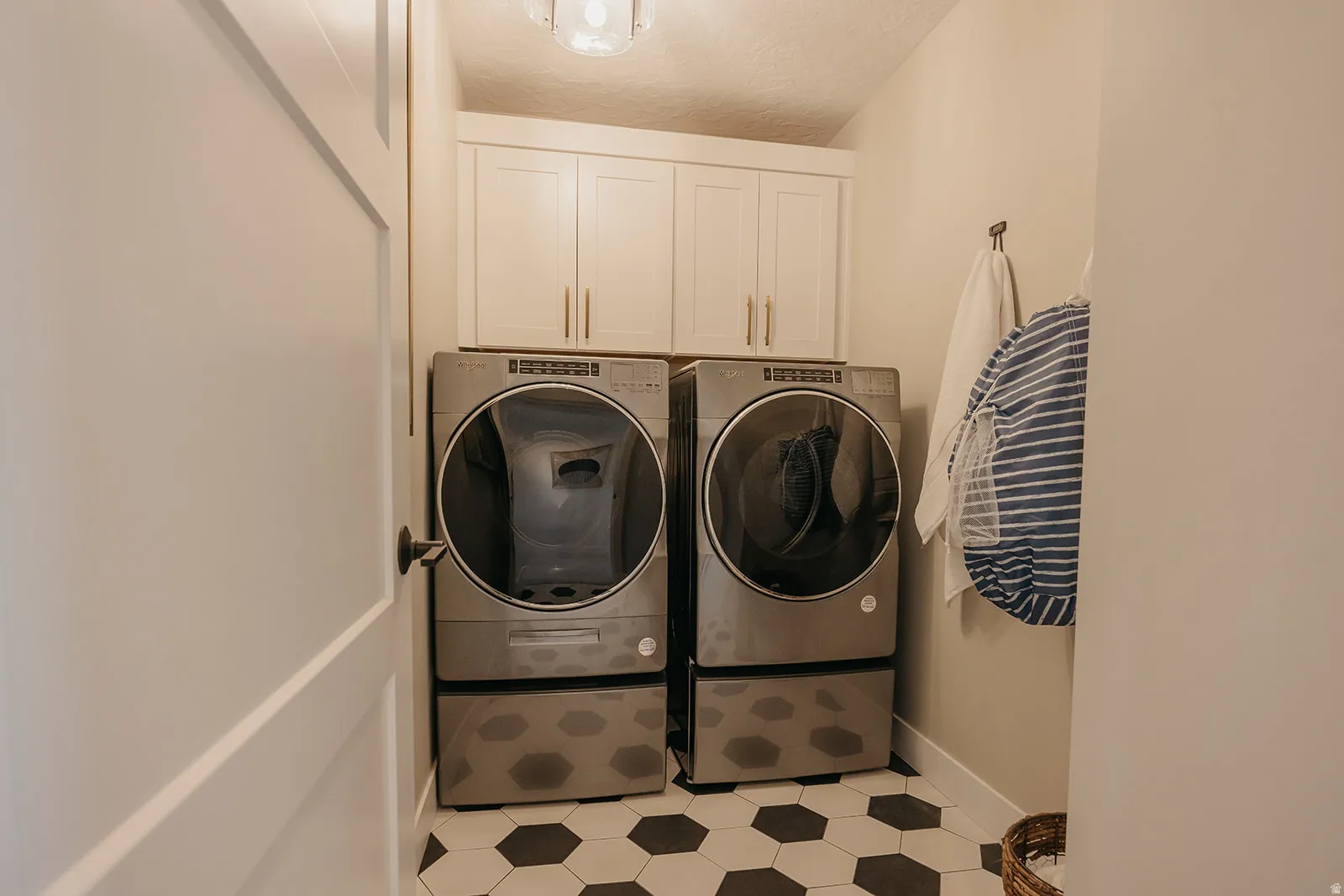 Laundry area featuring hexagonal tile flooring, upper cabinetry with brushed nickel hardware, and a ceiling-mounted light fixture