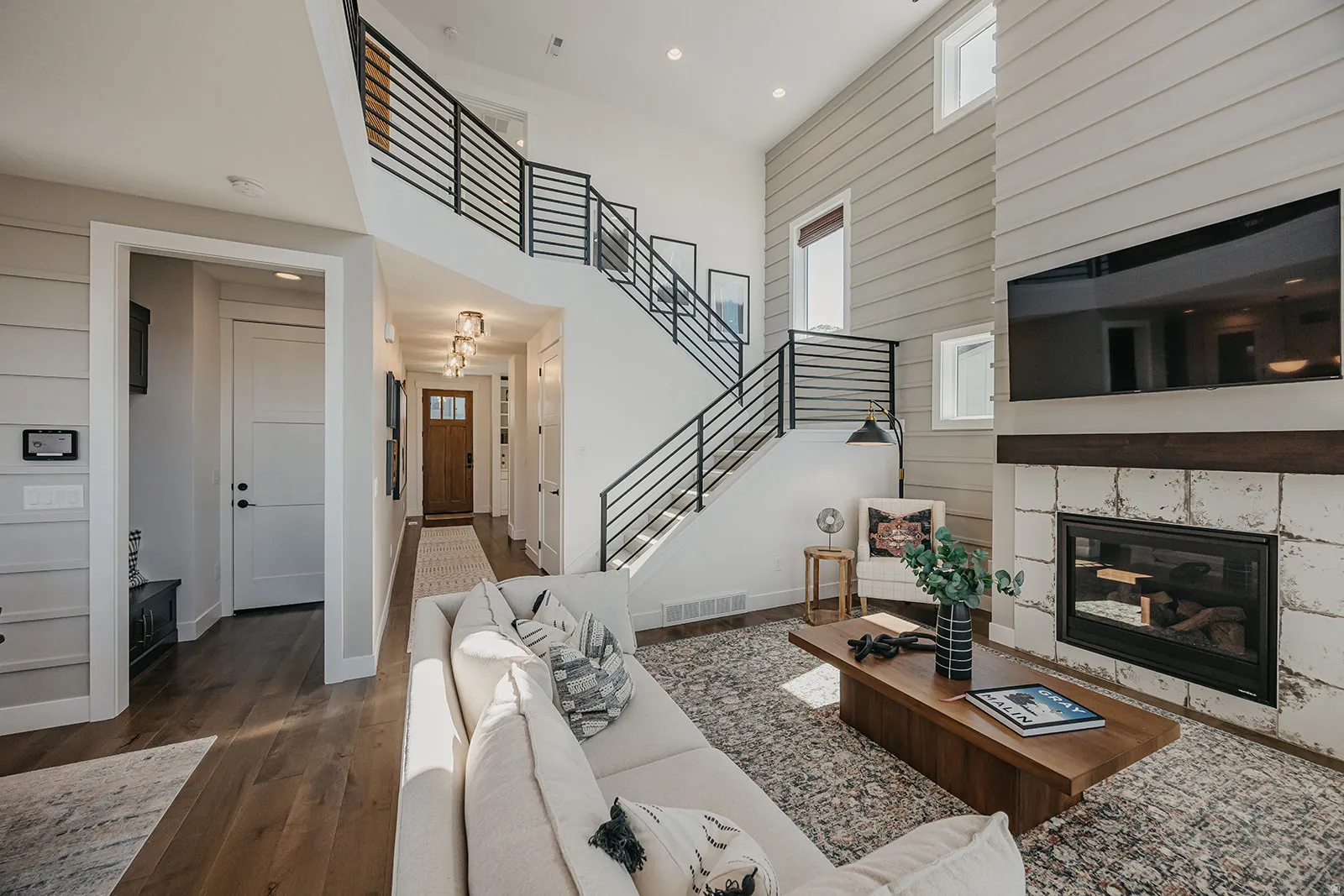 Two-story living area featuring a fireplace with a stone surround, a wood mantle, and a wall-mounted television space
