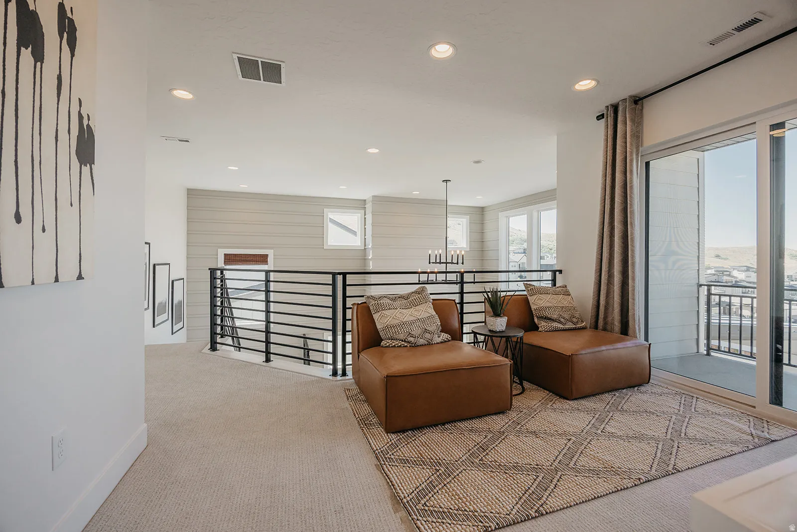 Upper-level landing featuring a sliding glass door to a private balcony, recessed lighting, and a modern horizontal railing system
