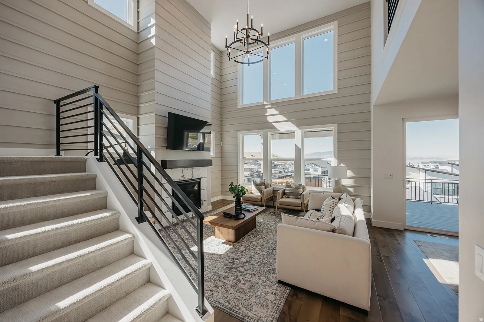 Two-story living area featuring a fireplace with stone surround, a wood mantel, and large picture windows