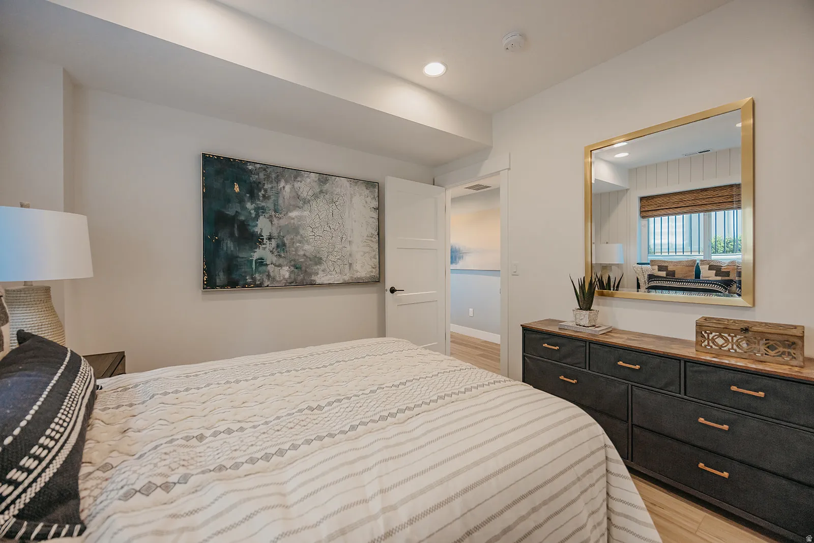 Recessed lighting illuminates this bright bedroom featuring wood-finish flooring