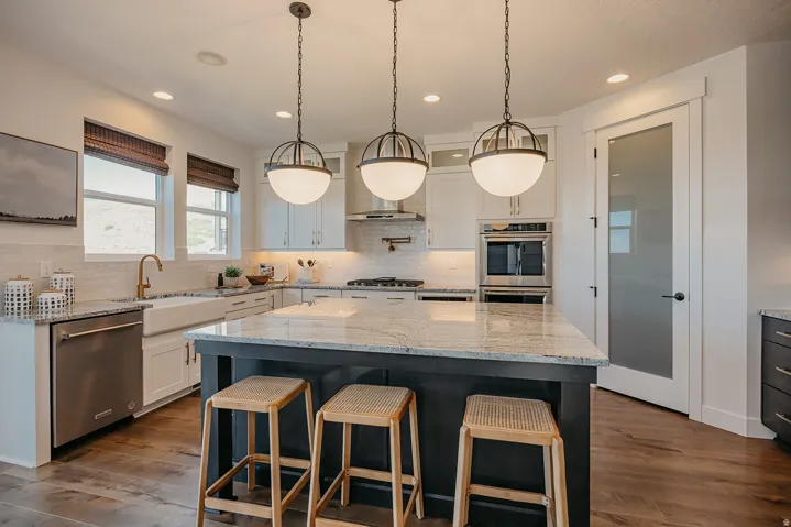 Kitchen featuring a central island with granite countertop, perimeter cabinetry, stainless steel appliances, and wood-finish flooring