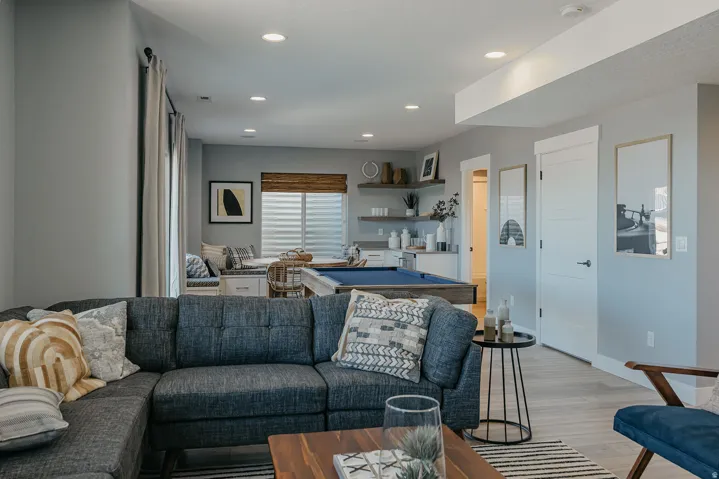 Open-concept lower level featuring recessed lighting, light wood-finish flooring, and a built-in wet bar with floating shelves