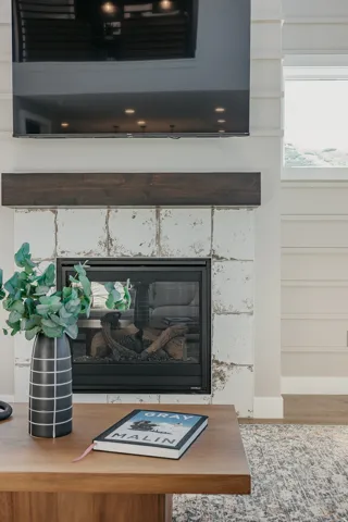 Built-in fireplace featuring a white distressed tile surround and a dark wood mantel